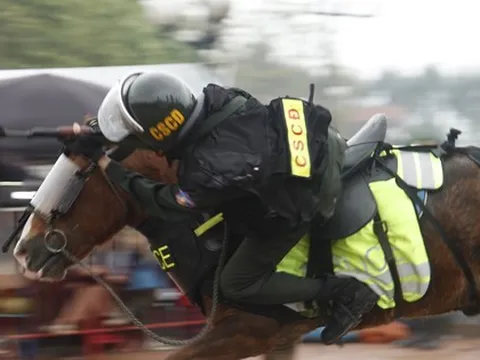 Cảnh sát cơ động kỵ binh rạp mình trên lưng ngựa, ngắm bắn súng AK